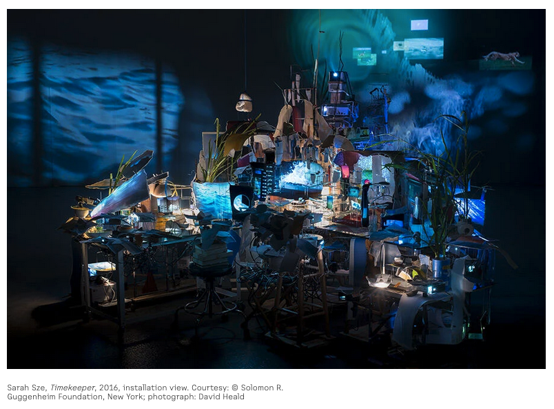 Screenshot of Sarah Sze's 2016 artwork Timekeeper, a visually chaotic installation of a desktop cluttered by many different objects